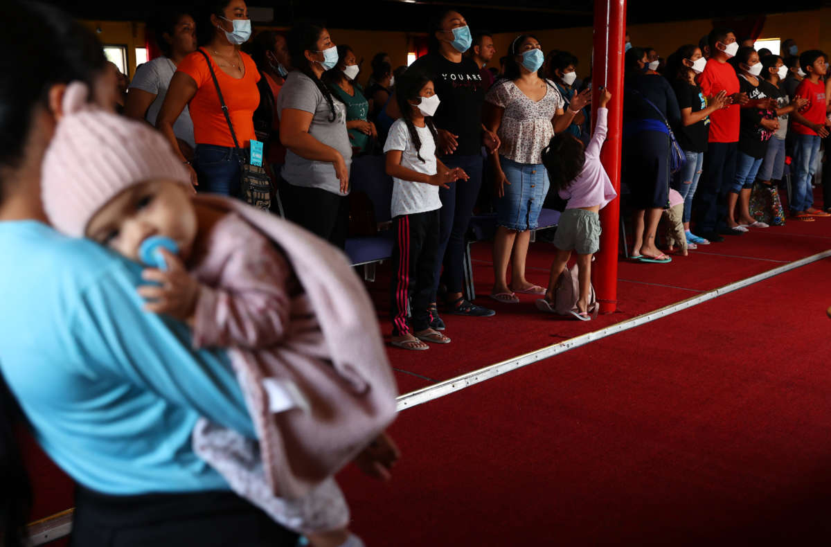 A 7-month-old migrant from Mexico is held by a family member as asylum-seeking migrants wear face coverings at a worship service in the Agape migrant shelter on July 22, 2021 in Tijuana, Mexico.