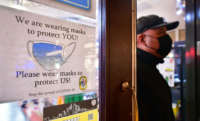 A man walks past a sign posted on a storefront reminding people to wear masks, on February 25, 2022, in Los Angeles, California.