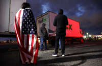 A supporter wears a US flag as truck drivers and supporters gather one day before a convoy departs for Washington, D.C., to protest COVID-19 mandates on February 22, 2022, in Adelanto, California.