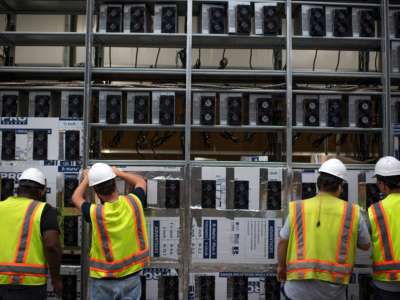 Workers install a new row of Bitcoin mining machines at the Whinstone U.S. Bitcoin mining facility in Rockdale, Texas, on October 9, 2021.