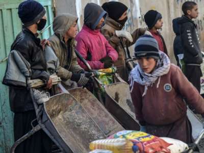 People wait to receive aid provided by a charity on the outskirts of Kabul, Afghanistan, on January 30, 2022.