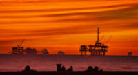 The sun sets over container ships and oil platforms off the coast of Huntington Beach, California, on January 12, 2021.