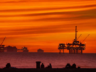 The sun sets over container ships and oil platforms off the coast of Huntington Beach, California, on January 12, 2021.