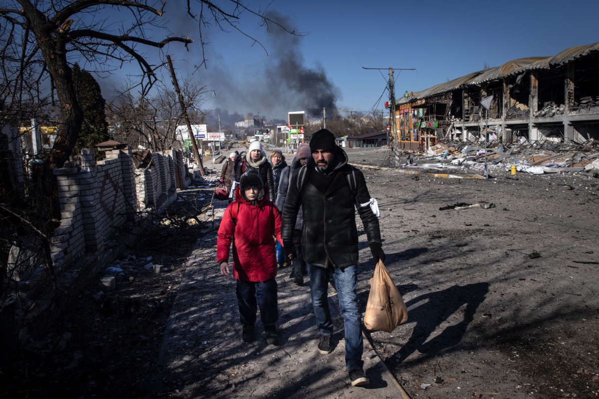 People walk amid destruction as they evacuate from a contested frontline area between Bucha and Irpin on March 10, 2022, in Irpin, Ukraine.