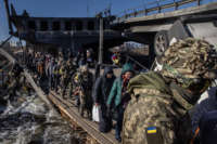 Residents of Irpin and Bucha flee fighting via a destroyed bridge on March 10, 2022, in Irpin, Ukraine.
