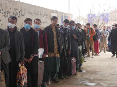 Afghans stand in line to leave the country