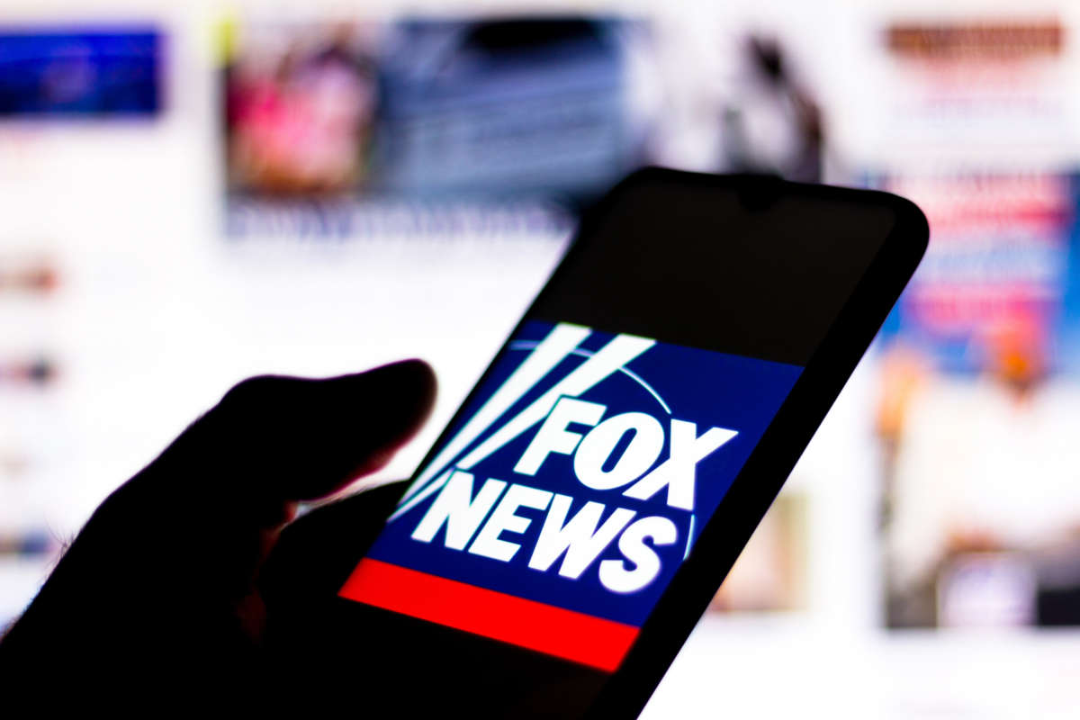 Hand holding cell phone with Fox News logo on display