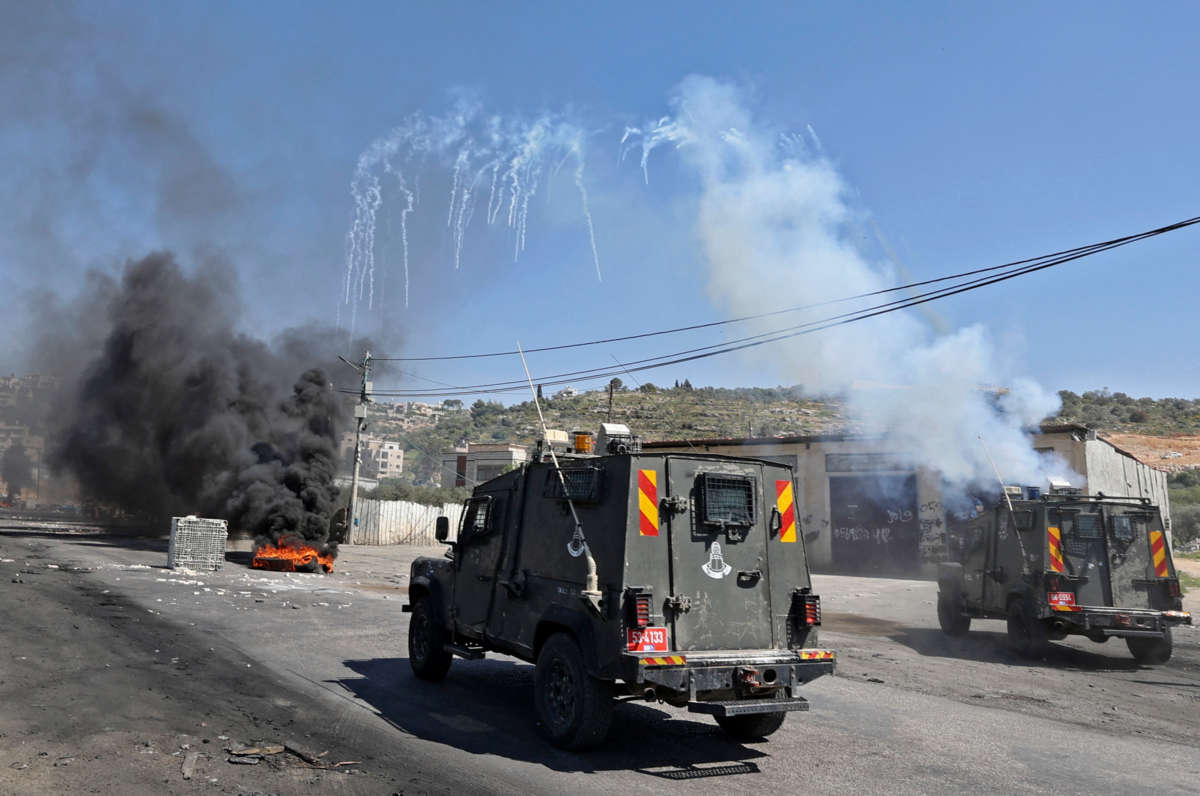 Israeli security members fire tear gas from vehicles on the main street of Beita village in the occupied West Bank on April 15, 2022, amid clashes with Palestinian protesters during a demonstration against Jewish settlements and in support of Jerusalem's Al Aqsa mosque.