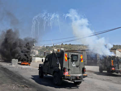 Israeli security members fire tear gas from vehicles on the main street of Beita village in the occupied West Bank on April 15, 2022, amid clashes with Palestinian protesters during a demonstration against Jewish settlements and in support of Jerusalem's Al Aqsa mosque.