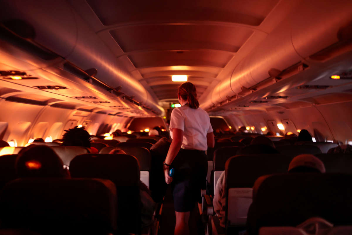 A flight attendant walks through an airplane before the plane's descent into the Dallas/Fort Worth International Airport on November 24, 2021, in Dallas, Texas.