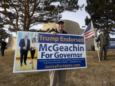 A supporter of Idaho's Lieutenant Governor Janice McGeachin's campaign for governor holds a sign picturing the candidate alongside Donald Trump on March 19, 2022, in Idaho Falls, Idaho.