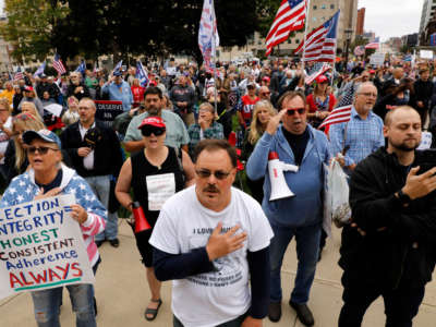 Protesters sing the U.S. National Anthem as they call for a "forensic audit" of the 2020 presidential election, during a demonstration by a group called Election Integrity Fund and Force outside of the Michigan State Capitol, in Lansing, Michigan, on October 12, 2021.