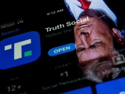 This photo illustration shows an image of former President Donald Trump reflected in a phone screen that is displaying the Truth Social app, in Washington, D.C., on February 21, 2022.