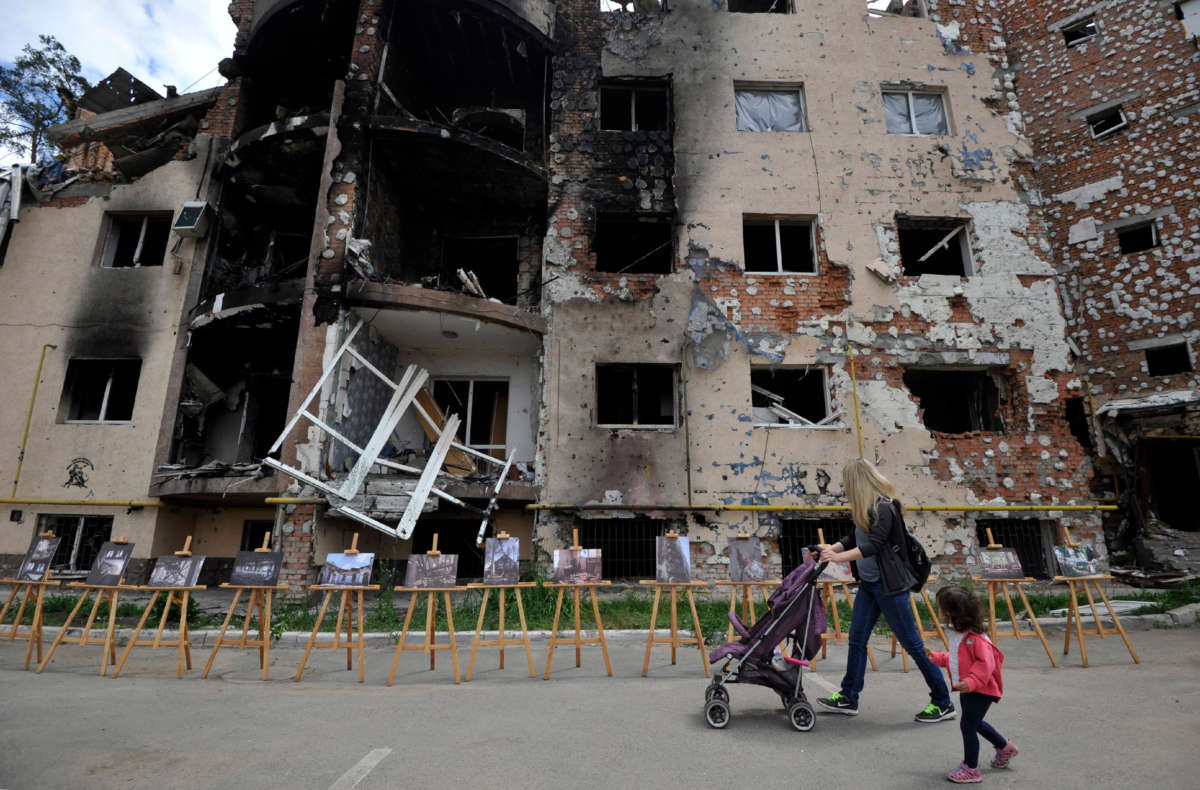 A woman and her daughter walk past a residential building destroyed as a result of shelling in the town of Irpin, near the Ukrainian capital of Kyiv on June 16, 2022.