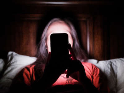 Woman laying in bed and checking updates on smartphone.