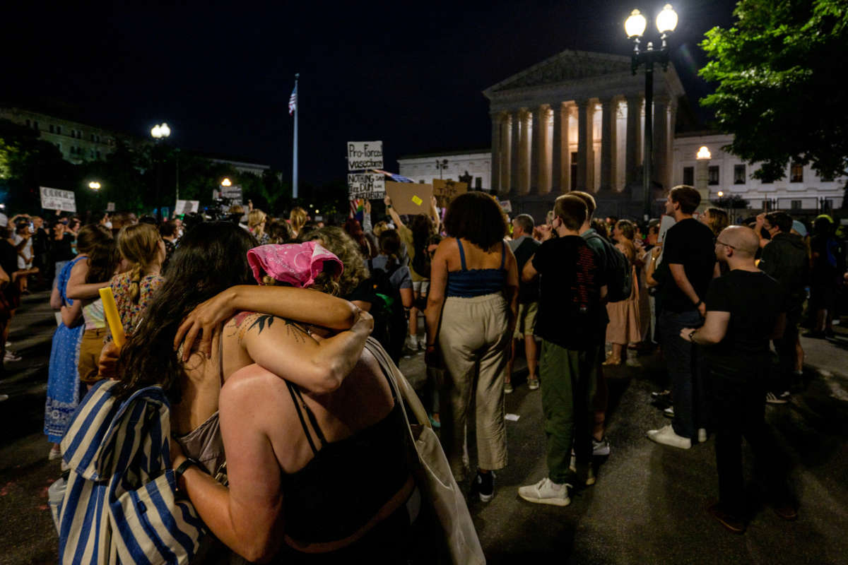 People embrace during a candlelight vigil in front of the U.S. Supreme Court to denounce the court's decision to end federal abortion rights protections on June 26, 2022, in Washington, D.C.