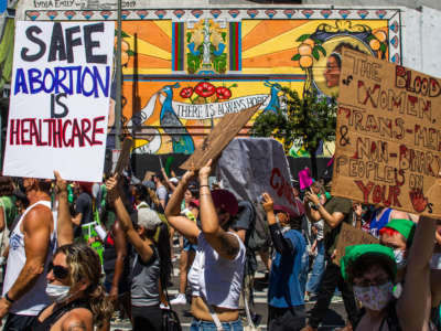 People hold placards as they protest in downtown Los Angeles on June 26, 2022.