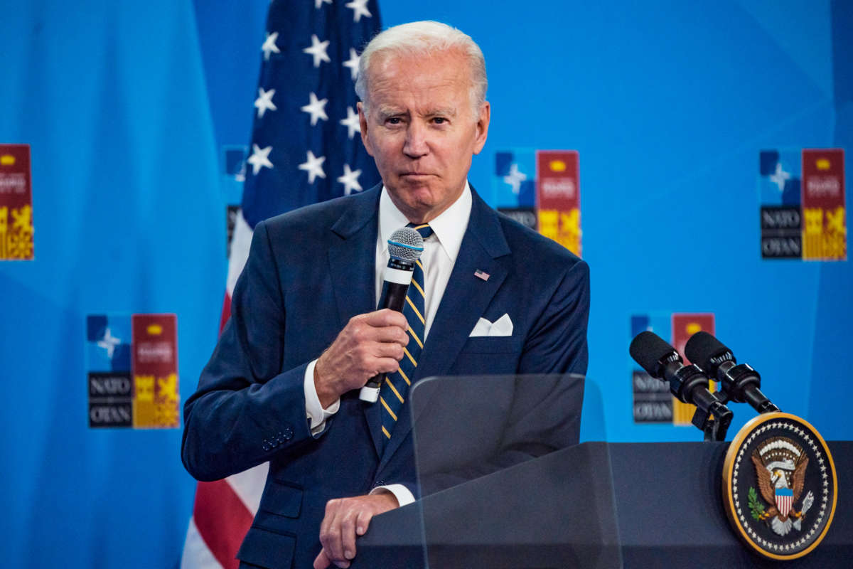 Joe Biden leans on a podium while speaking into a handheld mic