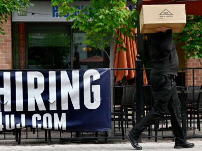 A man walks past a now hiring sign posted outside of a restaurant in Arlington, Virginia on June 3, 2022.