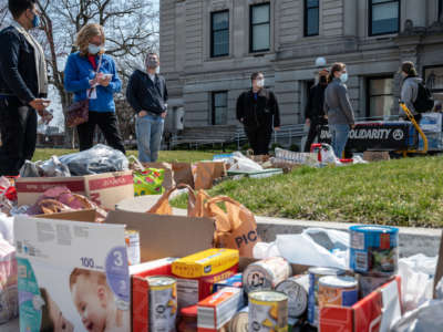 Activists take inventory of donated foods while others stand and talk during a Day of Solidarity event at the DeKalb County Court House on April 3, 2021, in Auburn, Indiana.