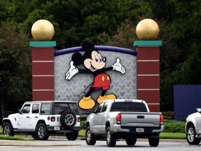 Cars drive past a sign featuring Mickey Mouse at the entrance to Walt Disney World in Lake Buena Vista, Florida, on July 11, 2020.