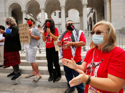 Elizabeth Blaney, right, with Union de Vecinos in the LA Tenants Union, chants with others as they listen to speakers talk about living unhoused from the steps of Los Angeles City Hall on May 19, 2021, in Los Angeles, California.