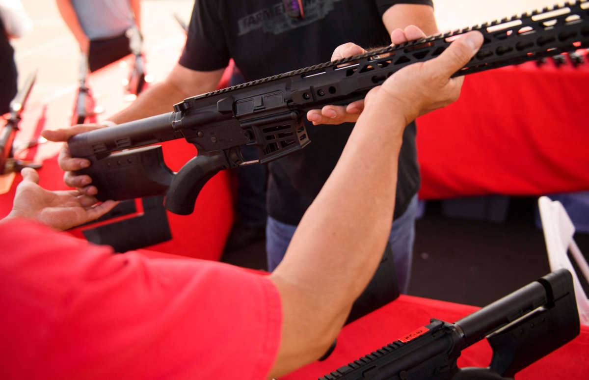 A clerk hands a customer a featureless AR-15 style rifle from TPM Arms LLC on display for sale at the company's booth at the Crossroads of the West Gun Show at the Orange County Fairgrounds on June 5, 2021, in Costa Mesa, California.