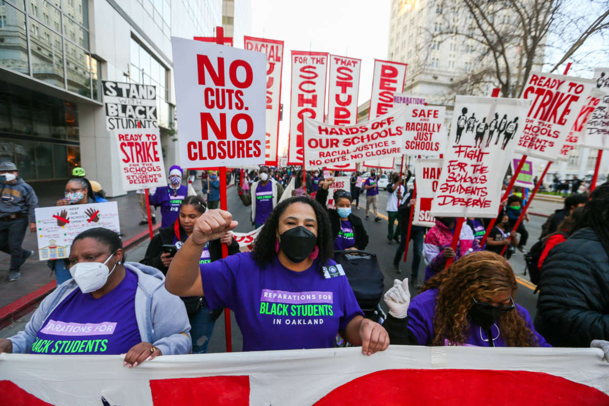 Parents in Oakland protest with signs that say "No cuts no closures"