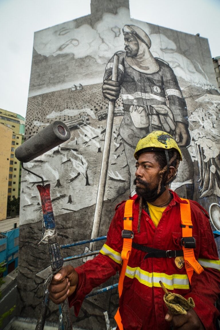 Vinicius Mendes, poses in front of the mural portraying him.