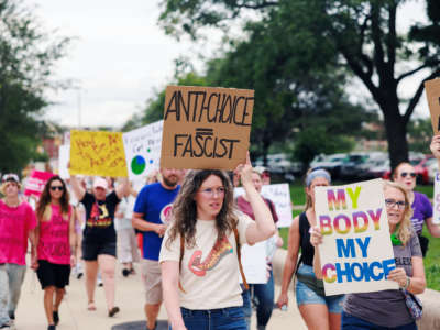 A person holds a sign reading "ANTI-CHOICE = FASCIST" during a protest