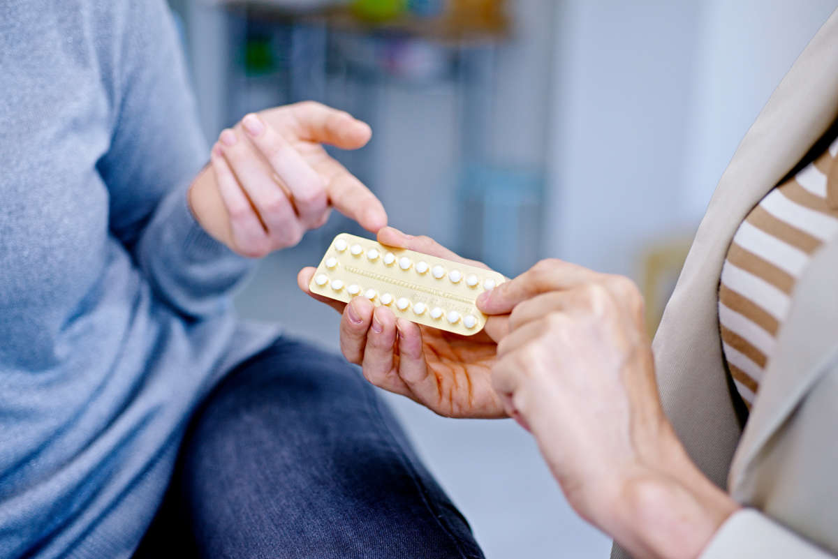 A doctor hands a patient a package of birth control pills