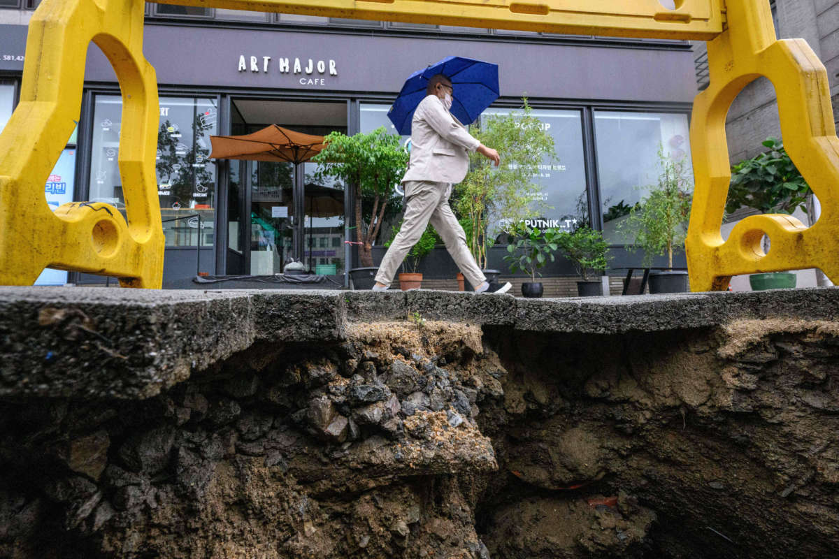 A man walks past a damaged pavement in Seoul, South Korea, on August 9, 2022, after record-breaking rains caused severe flooding.