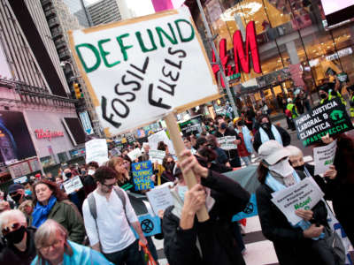 A sign reads 'Defund Fossil Fuels' at a climate crisis march in Times Square, New York