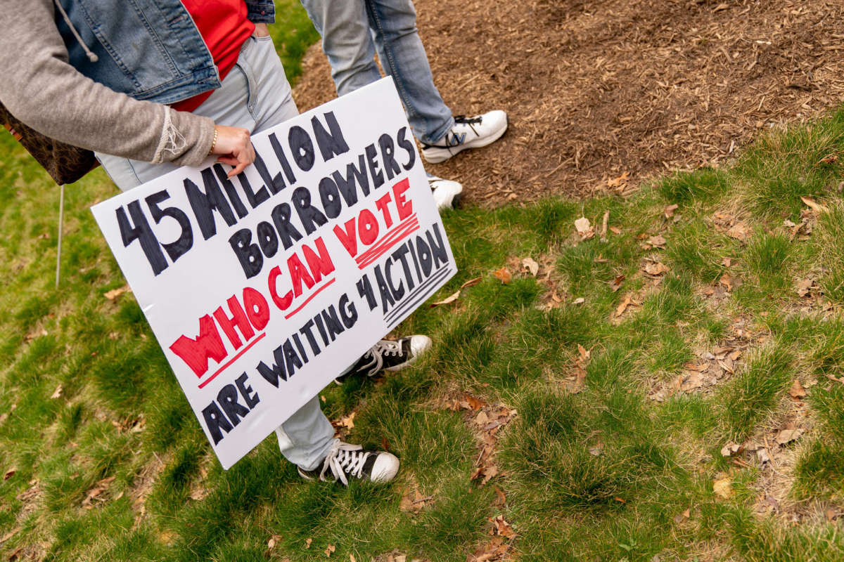 A sign that reads '45 million borrowers who can vote are waiting 4 action' is carried by a person at a Cancel Student Debt rally.