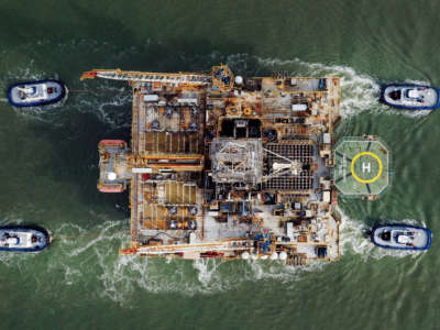 In this aerial image from a drone, tug boats tow the semi-submersible drilling platform Noble Danny Adkins through the Aransas Channel into the Gulf of Mexico on December 12, 2020, in Port Aransas, Texas.