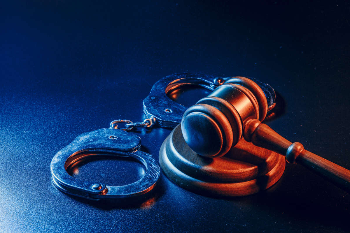 Handcuffs and gavel lit with blue and orange light