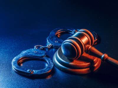 Handcuffs and gavel lit with blue and orange light