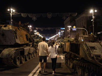 A couple walks by burnt-out Russian military vehicles displayed in the downtown area on August 22, 2022, in Kyiv, Ukraine.