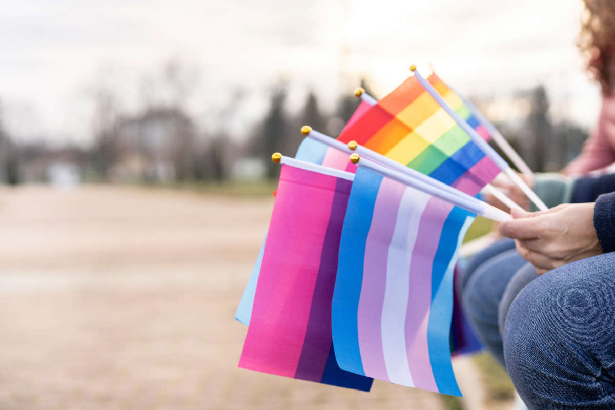 People sit with LGBTQ pride flags in hands