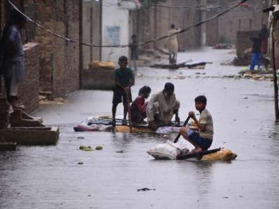 Residents use rafts to make their way along a waterlogged street in a residential area after a heavy monsoon rainfall in Hyderabad in the Sindh province of Pakistan, on August 24, 2022. Record monsoon rains were causing a "catastrophe of epic scale," and floods have killed more than 800 people since June.