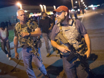 Oath Keepers, carrying rifles, walk along West Florrisant Street as demonstrators protest on August 10, 2015, in Ferguson, Missouri.