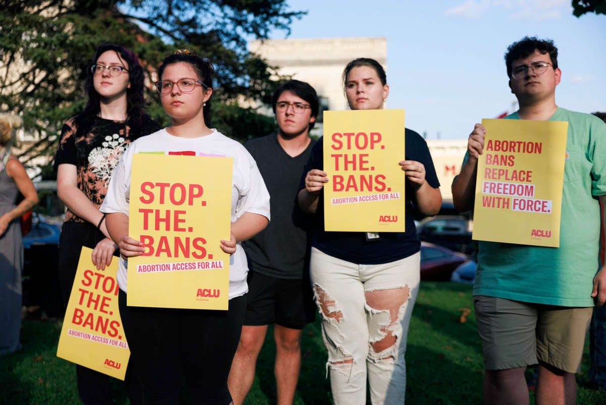 People hold signs reading "STOP THE BANS; ABORTION ACCESS FOR ALL" during a protest