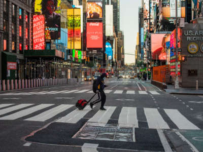 Pedestrians walk through en empty Times Square on March 27, 2020, in New York City.