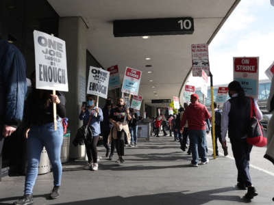 San Francisco International Airport food service workers carry signs as they strike outside of a terminal at the airport on September 26, 2022, in San Francisco, California.
