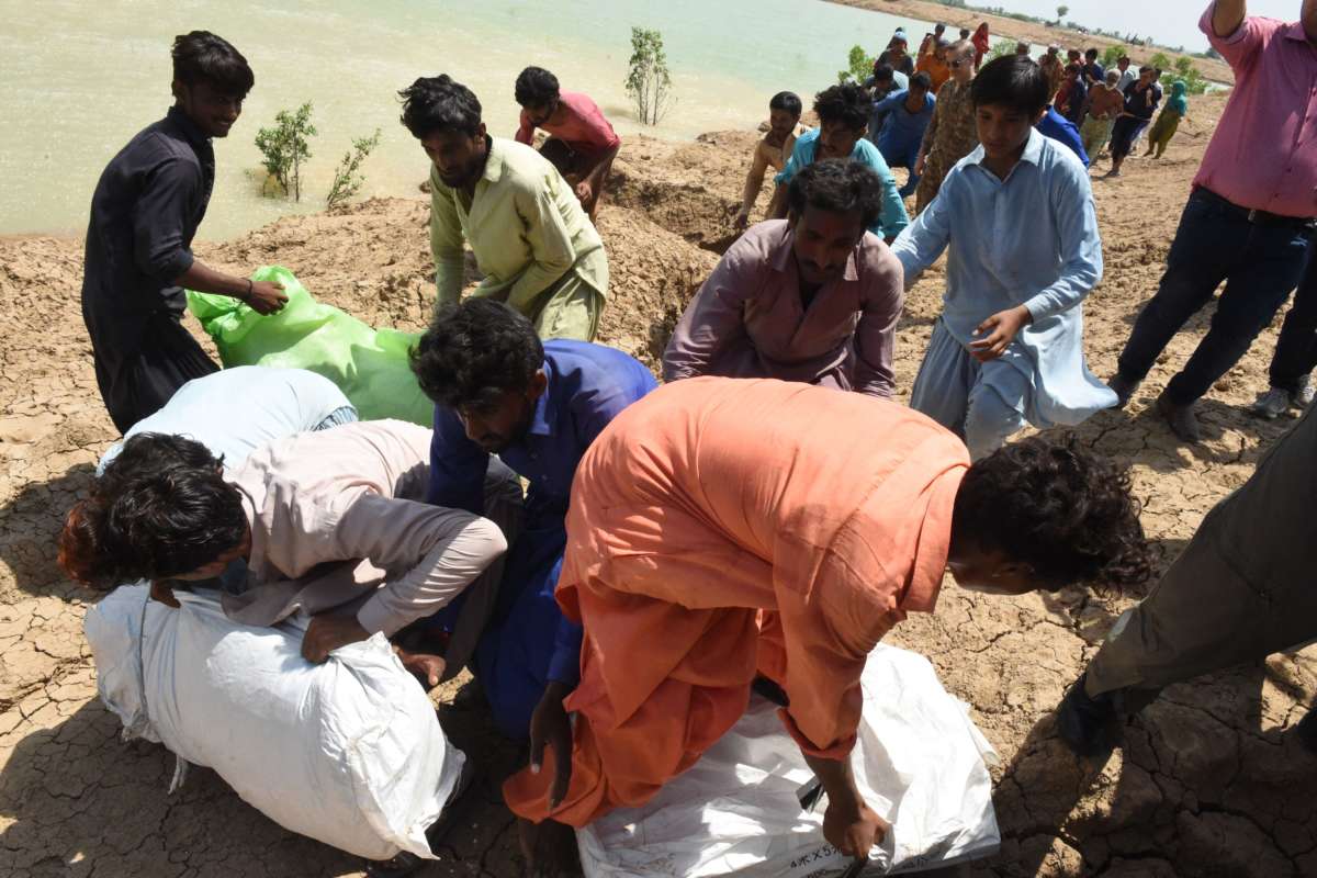 This aerial photograph taken on September 3, 2022, shows flood-affected people as they collect relief bags given by Pakistan army from a helicopter after heavy monsoon rains in Jaffarabad district, Balochistan province.