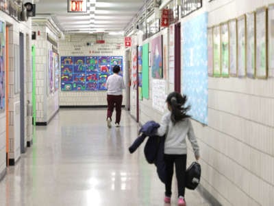 Principal Alice Hom walks down a hallway followed by a student at Yung Wing School P.S. 124 on April 11, 2022, in New York City.