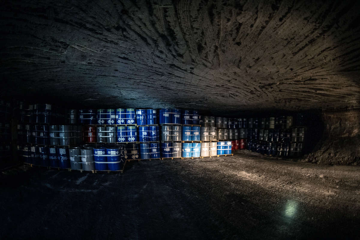 Stacked barrells of toxic waste line the claustrophobic interior of an underground storage bunker