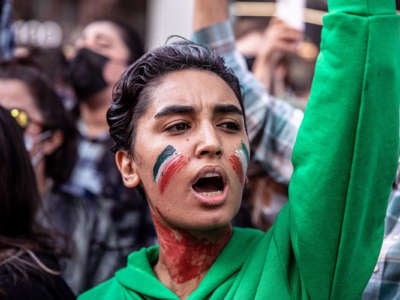 A protester with the Iranian flag painted on their face participates in an outdoor demonstration