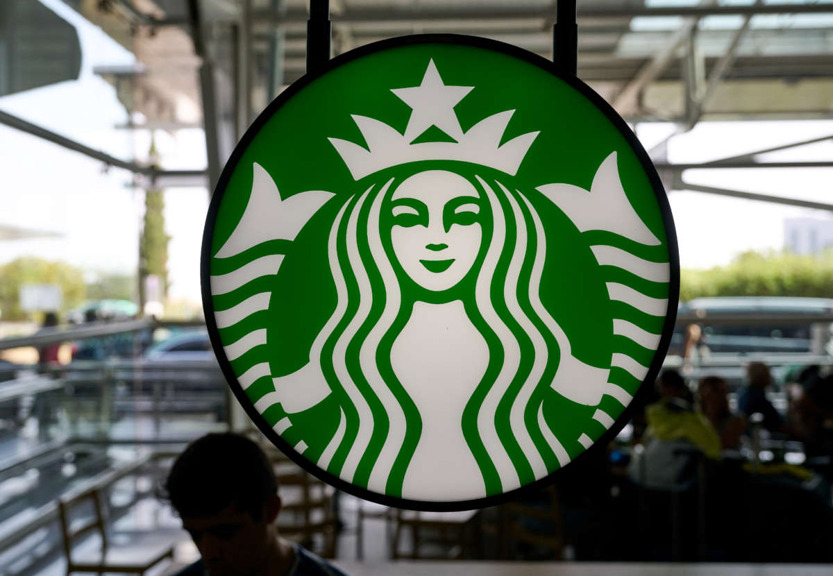 Travelers are silhouetted while sitting under Starbucks Coffee logo in the arrivals hall at Terminal 1 in Humberto Delgado International Airport Humberto Delgado International Airport on October 7, 2022, in Lisbon, Portugal.