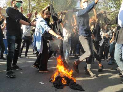 Iranian protesters set their scarves on fire while marching down a street on October 1, 2022, in Tehran, Iran.